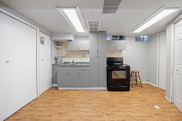 kitchen featuring gray cabinetry, tasteful backsplash, black electric range oven, light hardwood / wood-style flooring, and sink