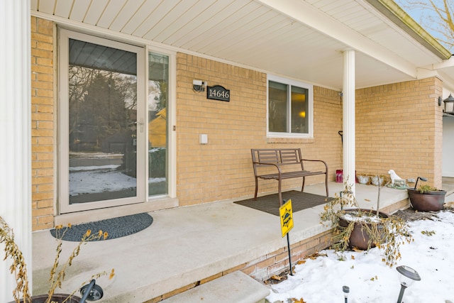 snow covered property entrance featuring covered porch