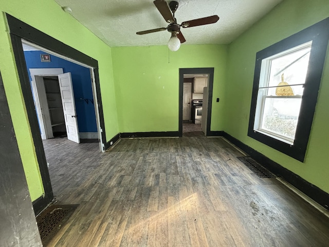 empty room with a textured ceiling, ceiling fan, and dark hardwood / wood-style flooring