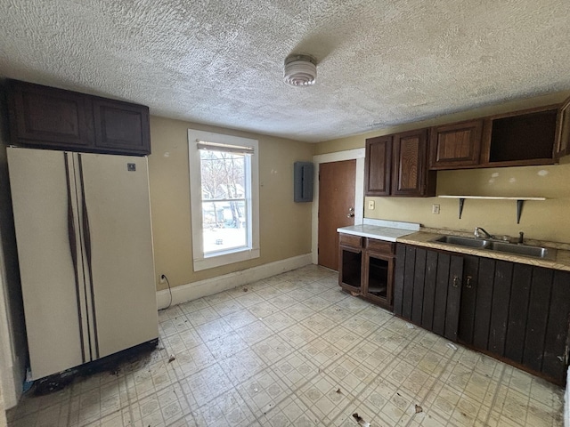 kitchen with dark brown cabinets, sink, white fridge, and a textured ceiling