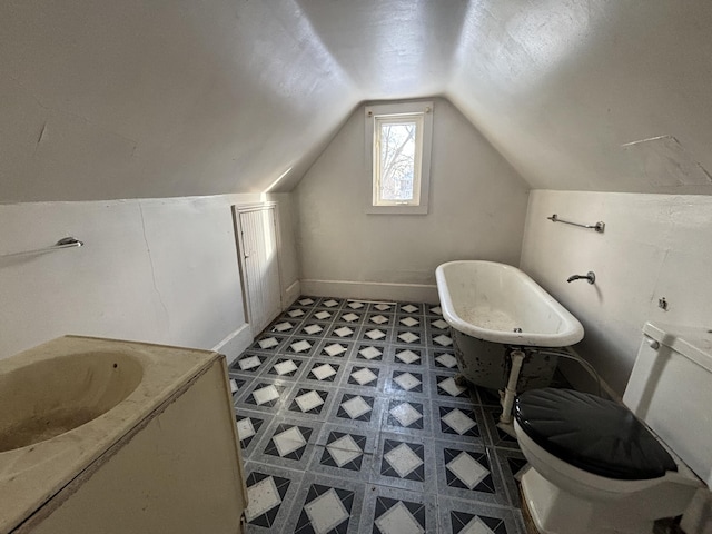 bathroom featuring a tub to relax in, vanity, lofted ceiling, and toilet