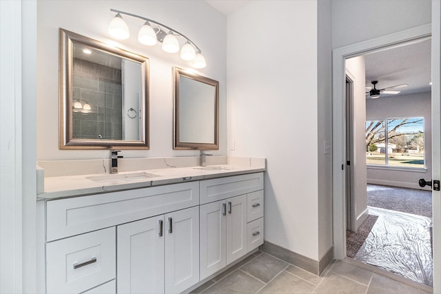 full bath with tile patterned flooring, a sink, baseboards, and double vanity