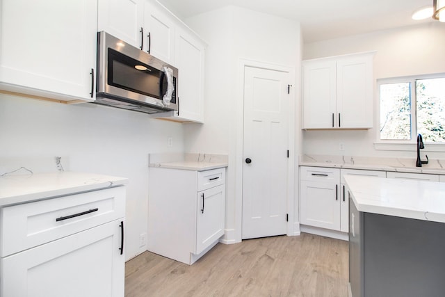 kitchen with stainless steel microwave, a sink, and white cabinetry