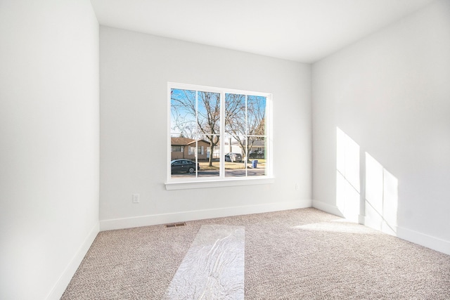 carpeted empty room featuring visible vents and baseboards