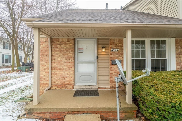 snow covered property entrance with a porch