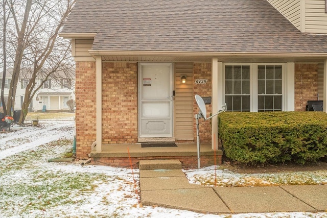 snow covered property entrance featuring a porch