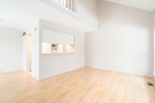 unfurnished living room with a high ceiling and light wood-type flooring