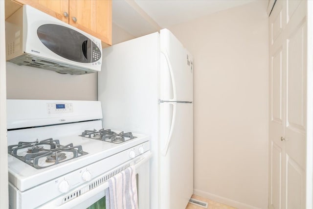 kitchen featuring white gas range oven and light brown cabinets