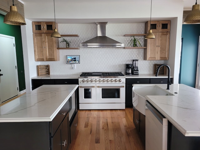 kitchen featuring light stone countertops, dishwasher, wall chimney exhaust hood, decorative light fixtures, and range with two ovens