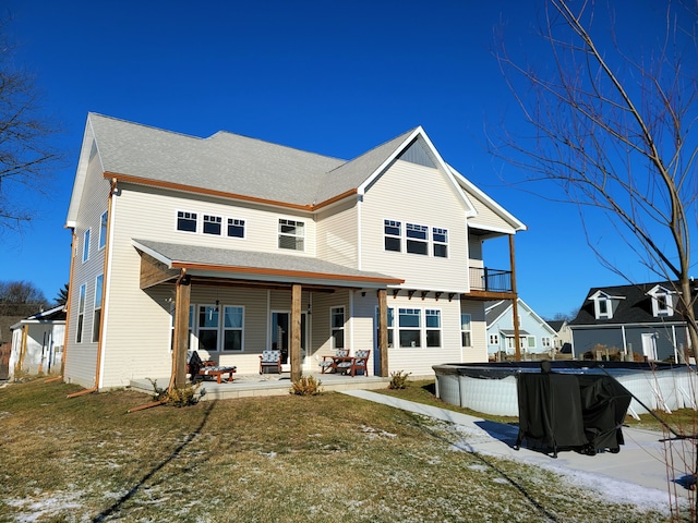 rear view of property with roof with shingles, a pool, a lawn, and a patio