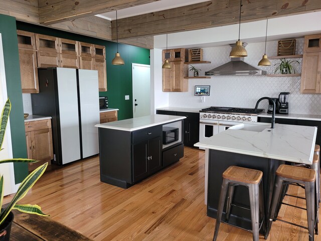 kitchen featuring double oven range, a center island with sink, decorative light fixtures, light wood-type flooring, and black microwave