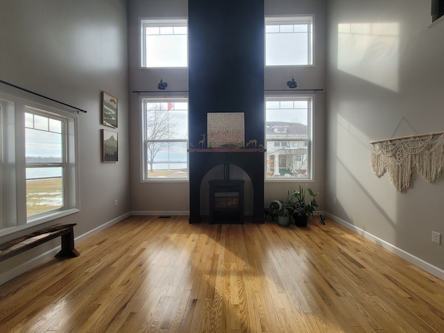 unfurnished living room featuring a towering ceiling, plenty of natural light, and light hardwood / wood-style floors