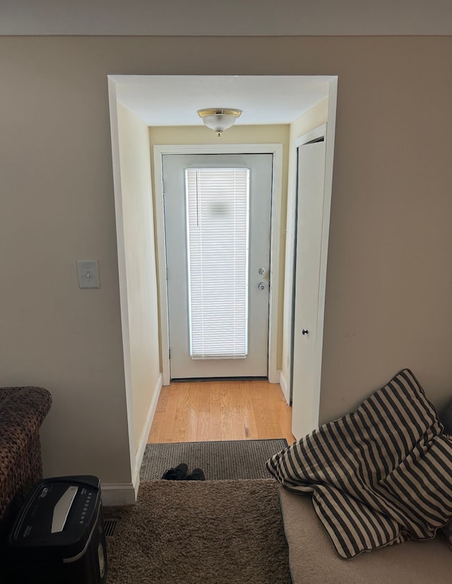 entryway with light wood-style floors, light colored carpet, and baseboards