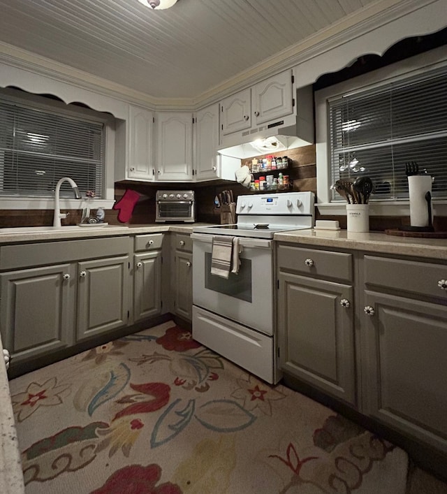 kitchen with white electric range oven, ornamental molding, gray cabinets, under cabinet range hood, and a sink