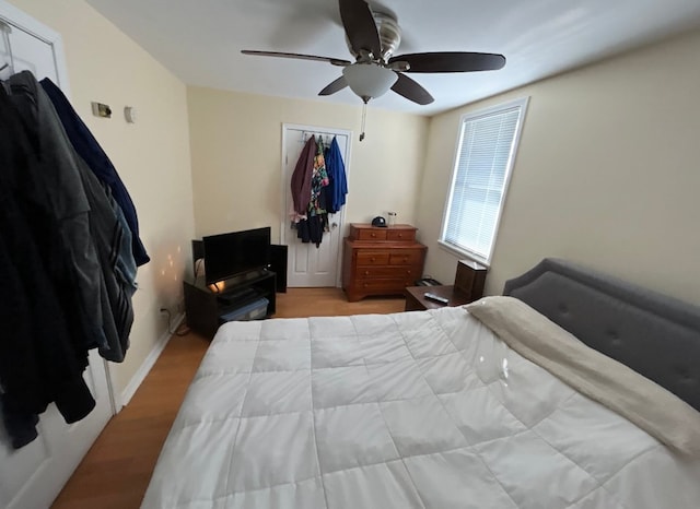 bedroom featuring light wood-style floors, ceiling fan, baseboards, and a closet