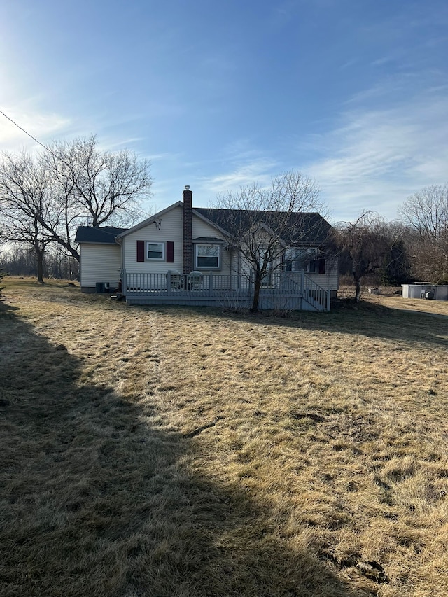 back of house with a wooden deck, a lawn, and a chimney