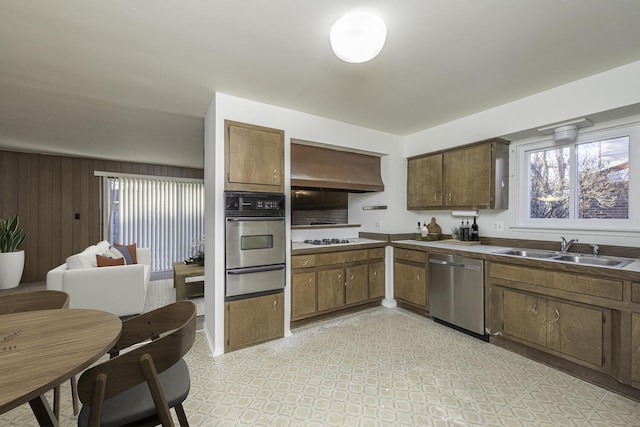 kitchen featuring sink, appliances with stainless steel finishes, wood walls, and extractor fan