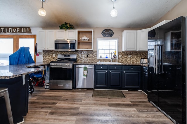 kitchen with appliances with stainless steel finishes, white cabinetry, and hanging light fixtures