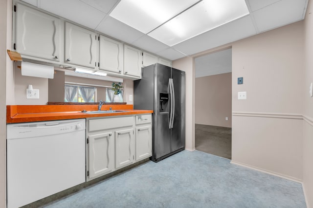 kitchen with stainless steel fridge, dishwasher, sink, white cabinetry, and a drop ceiling