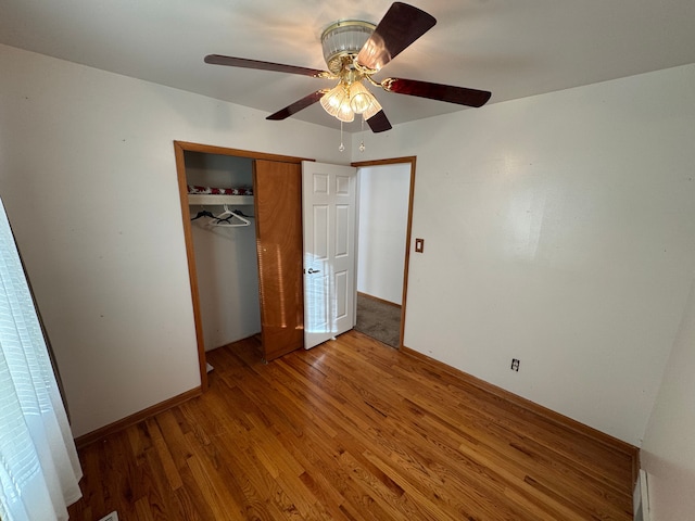 unfurnished bedroom featuring ceiling fan, a closet, and hardwood / wood-style flooring