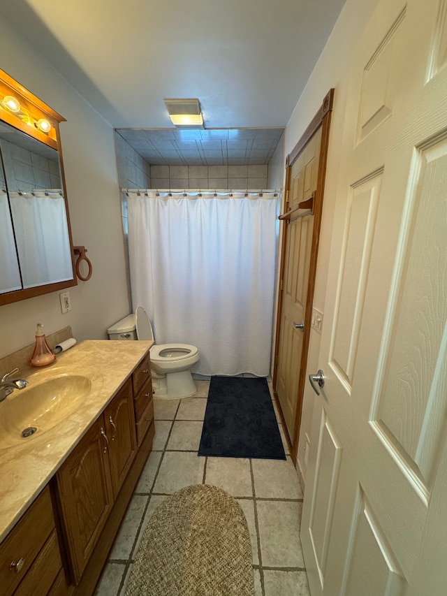 bathroom with toilet, vanity, tile patterned flooring, and curtained shower