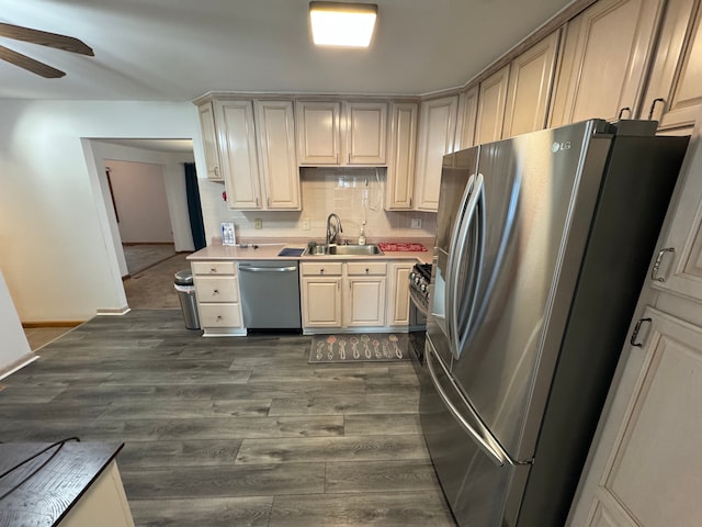 kitchen featuring stainless steel appliances, decorative backsplash, sink, dark hardwood / wood-style floors, and ceiling fan