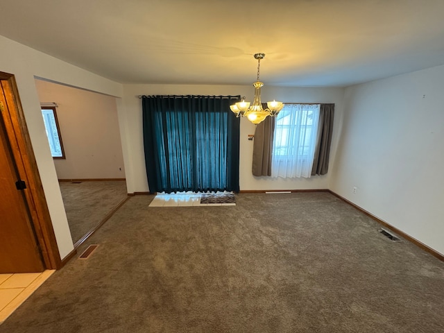 carpeted spare room with a chandelier