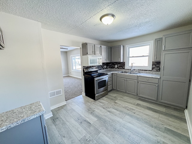 kitchen with stainless steel range with electric cooktop, decorative backsplash, gray cabinetry, and sink