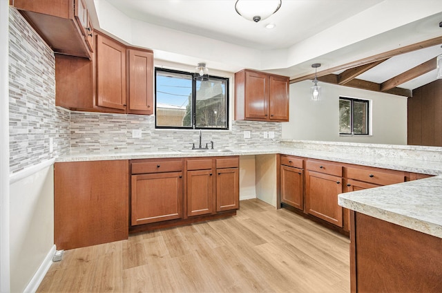 kitchen featuring light hardwood / wood-style floors, kitchen peninsula, decorative backsplash, pendant lighting, and sink