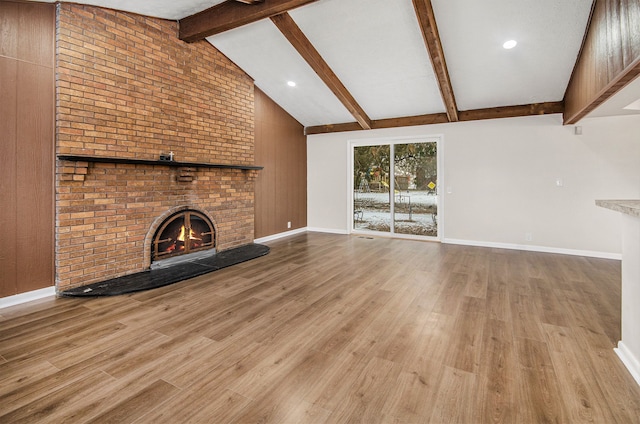 unfurnished living room featuring a brick fireplace, high vaulted ceiling, beamed ceiling, and light wood-type flooring