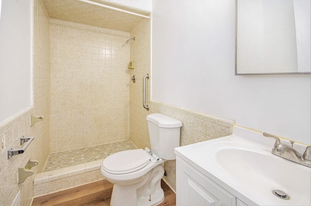 bathroom featuring vanity, tile walls, toilet, hardwood / wood-style flooring, and a tile shower