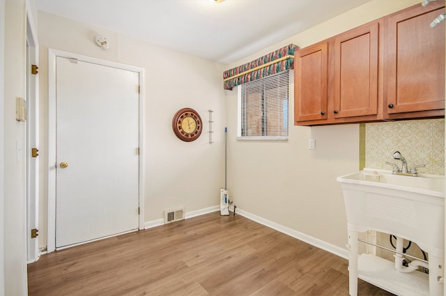 clothes washing area with light hardwood / wood-style flooring