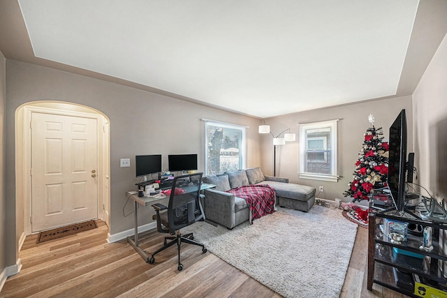 living room featuring wood finished floors, arched walkways, and baseboards