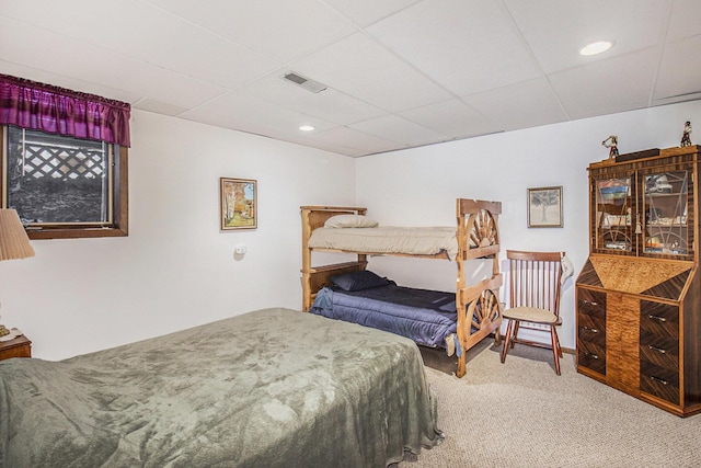 carpeted bedroom featuring a drop ceiling