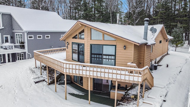 snow covered rear of property with central air condition unit and a deck