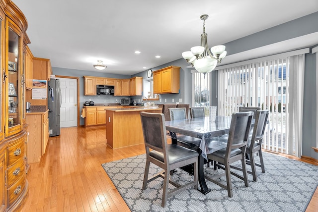 dining area with an inviting chandelier, light hardwood / wood-style floors, and sink