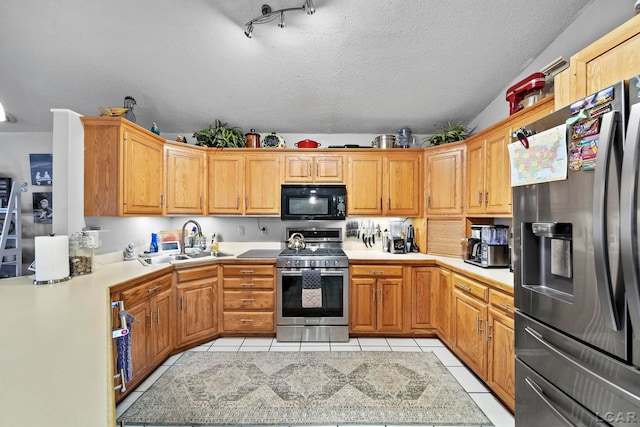 kitchen with sink, light tile patterned floors, appliances with stainless steel finishes, and a textured ceiling