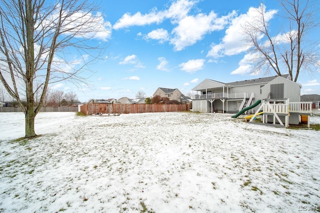 yard covered in snow featuring a playground and a wooden deck