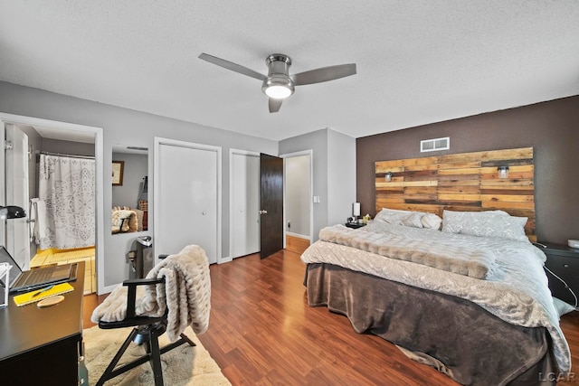 bedroom featuring hardwood / wood-style floors, a textured ceiling, two closets, and ceiling fan