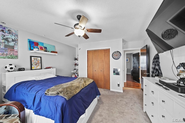 bedroom featuring light carpet, a textured ceiling, a closet, and ceiling fan