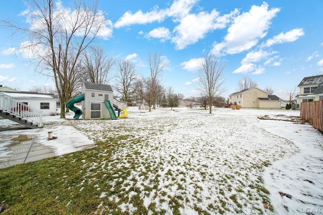 snowy yard featuring a playground