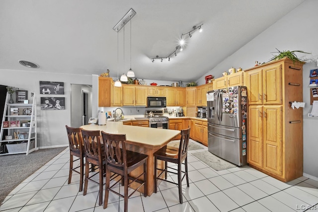 kitchen featuring decorative light fixtures, sink, a kitchen breakfast bar, and stainless steel appliances