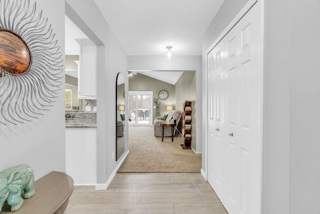 hallway with lofted ceiling and light hardwood / wood-style flooring