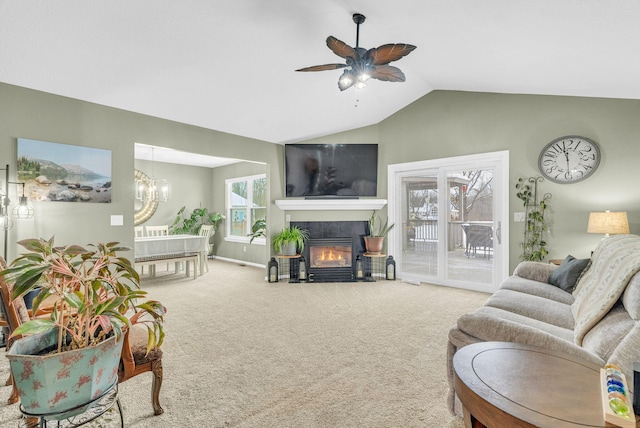 living room with lofted ceiling, carpet, a tile fireplace, and ceiling fan with notable chandelier