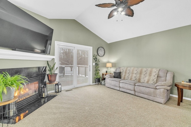 living room with carpet floors, a tiled fireplace, vaulted ceiling, and ceiling fan