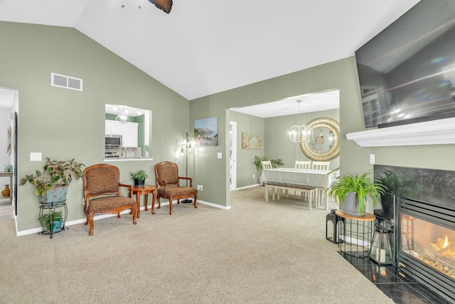 living area featuring carpet floors, vaulted ceiling, a notable chandelier, and a tile fireplace