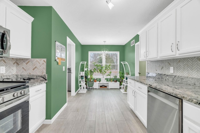 kitchen with white cabinetry, stainless steel appliances, decorative backsplash, hanging light fixtures, and light stone counters