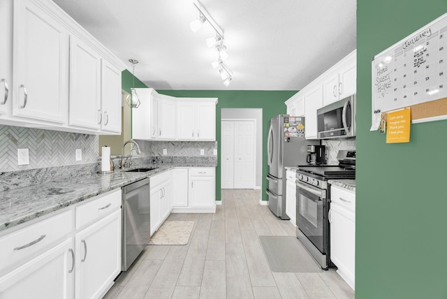 kitchen featuring sink, white cabinetry, stainless steel appliances, and hanging light fixtures