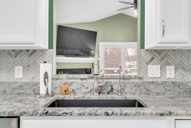 kitchen featuring white cabinets, sink, and light stone counters