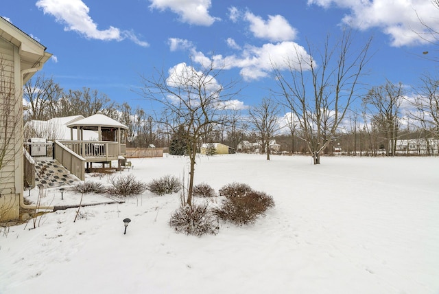 yard covered in snow featuring a gazebo and a wooden deck